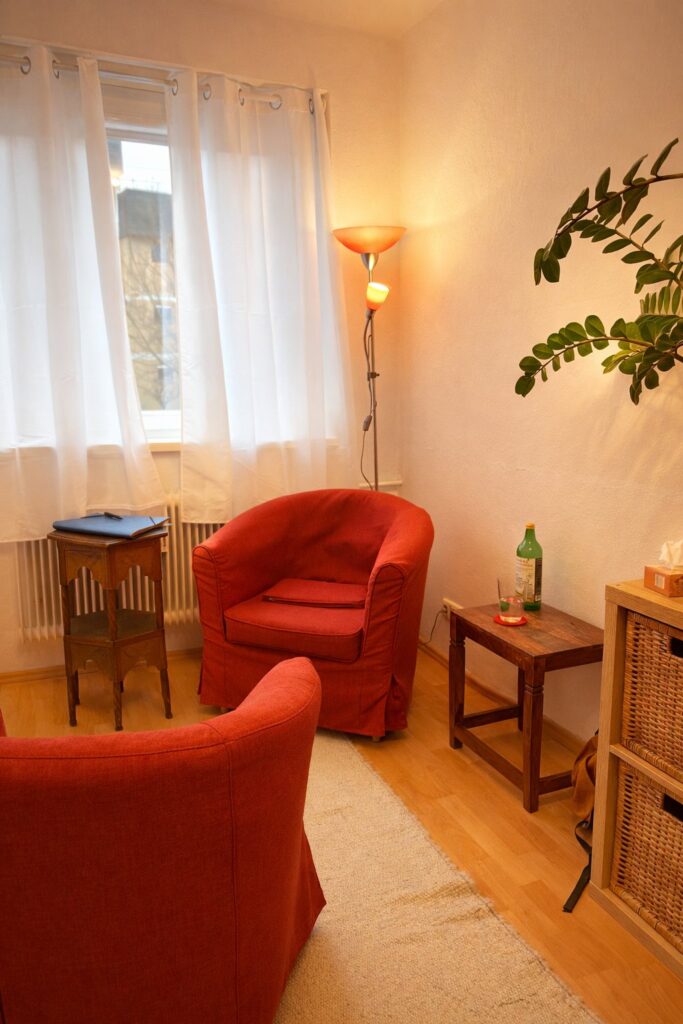 Sitzecke mit roten Sesseln im Praxisraum von NeoOsteo Graz